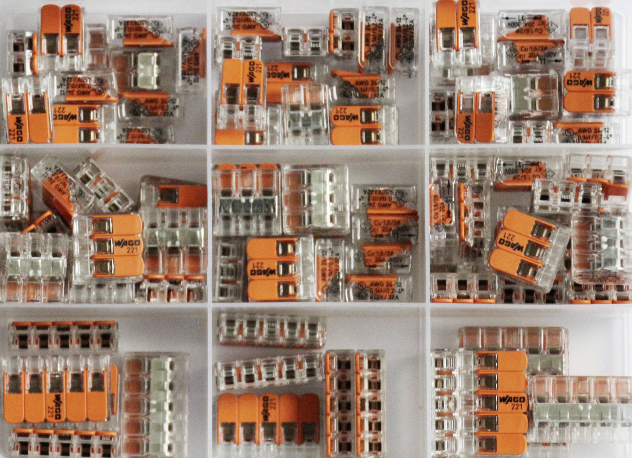 Transparent behållare med sorterade WAGO-klämmor i olika storlekar och former för elektrisk kabeldragning.