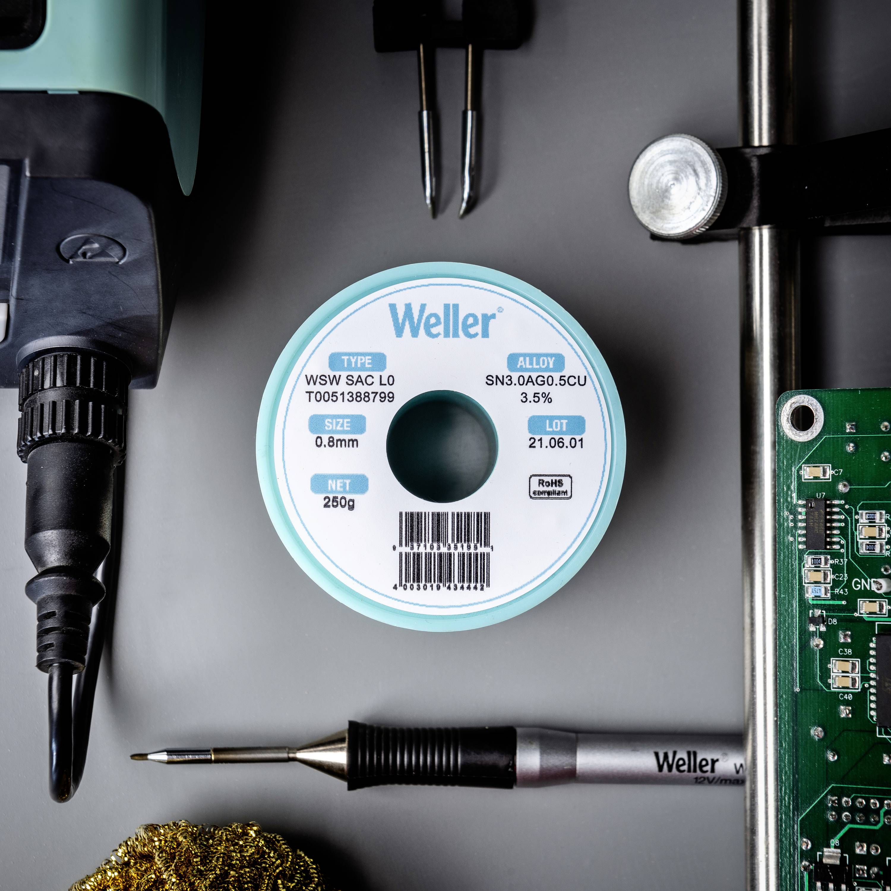 Lödstation med lödtenrulle från märket Weller. Bredvid lödkolvspets, kretskort och lödtillbehör. Verktyg för elektroniskt arbete visas.