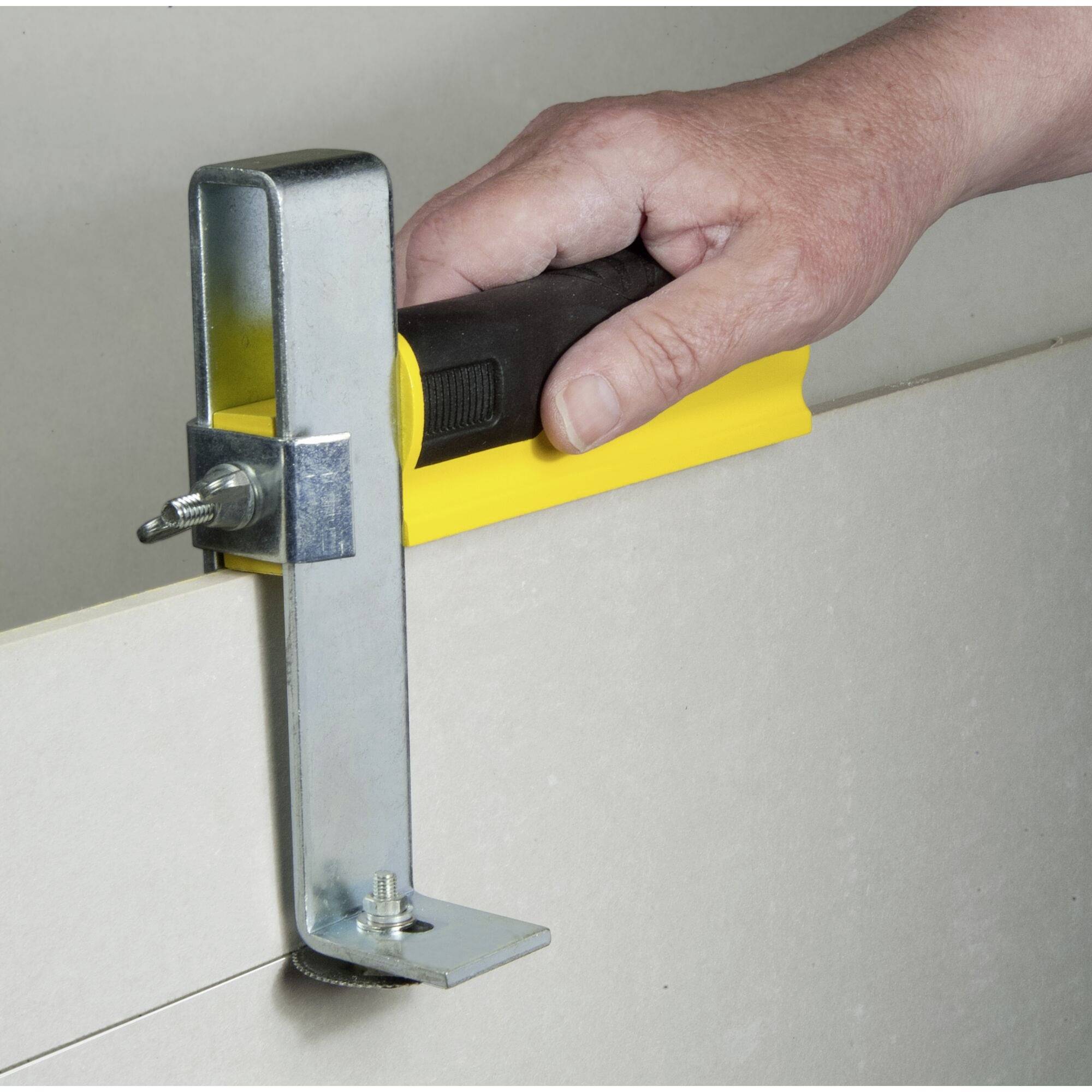 En hand håller ett verktyg som används för att noggrant skära gipsskivor.