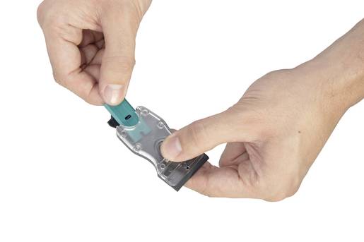 Två händer håller ett transparent plastfäste medan ett USB-minne sätts in i fästet.