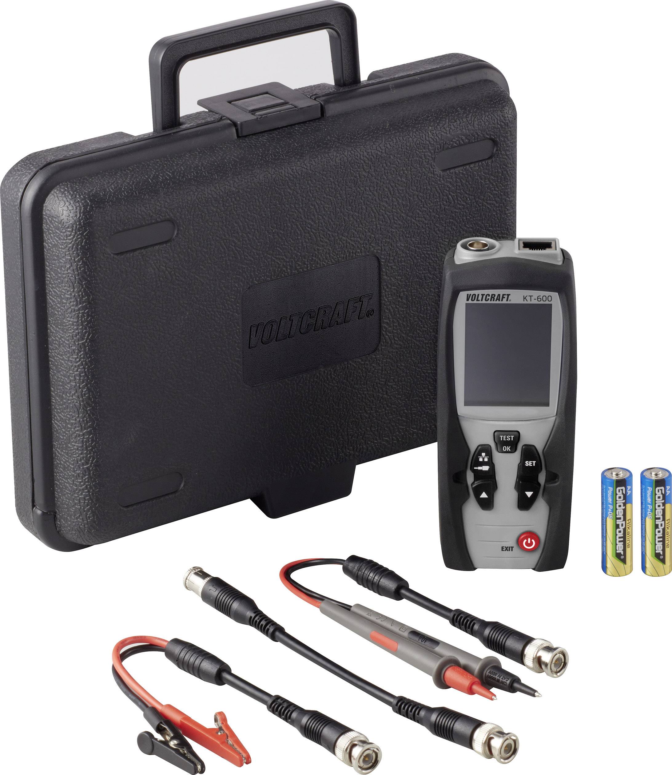 En digital Volcraft KT-100 mätare med tillbehör, inklusive kabel med krokodilklämmor och batterier, framför en transportabel väska.