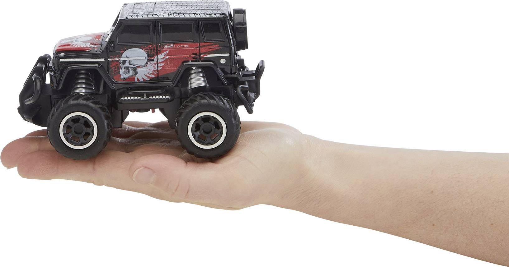 En utsträckt hand håller en liten leksaksbil i SUV-stil med iögonfallande röda och svarta grafiska detaljer på sidan.