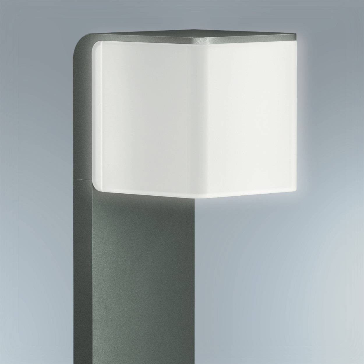 Modern utomhuslampa med rektangulär, vit lampskärm på grå fot framför blågrå bakgrund. Perfekt för trädgårdsbelysning.