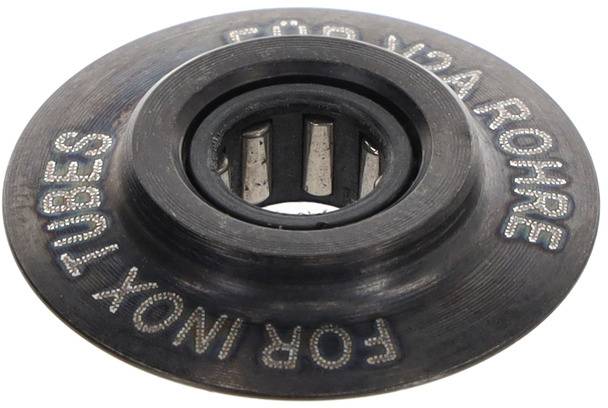 En metallskiva med inpräglad text 'FÖR INOX-RÖRLEDNINGAR FÖR INOX-RÖRLEDNINGAR' och ett centralt hål med ett lagermekanism.