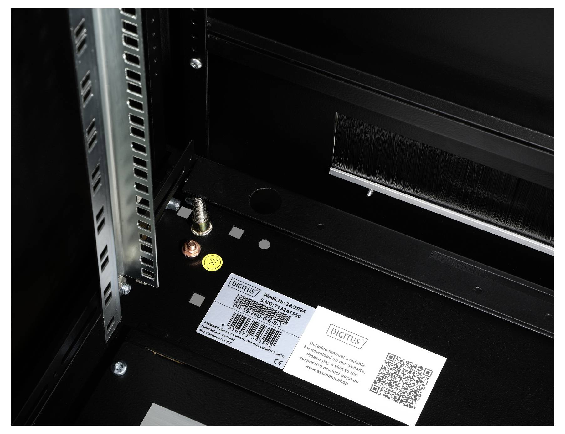 Ett serverrack med ett märke 'Digitus' och en QR-kod på en etikett. Märkning 'Model: DK-19xxM-SW'. Metallram synlig till vänster.