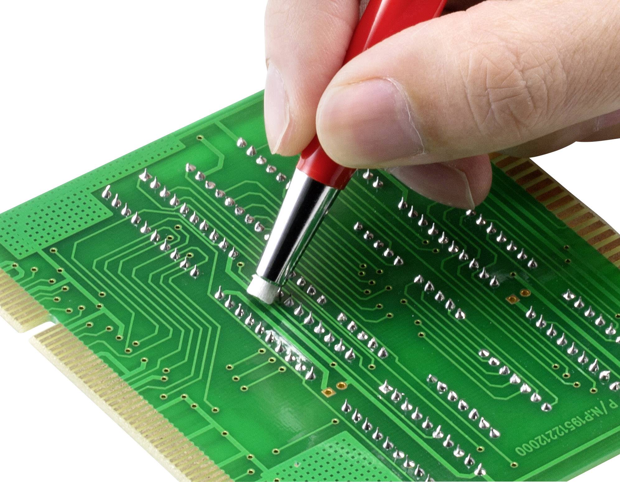 En hand använder ett rött antistatiskt verktyg för att rengöra eller bearbeta ledningsbanorna på ett grönt kretskort.