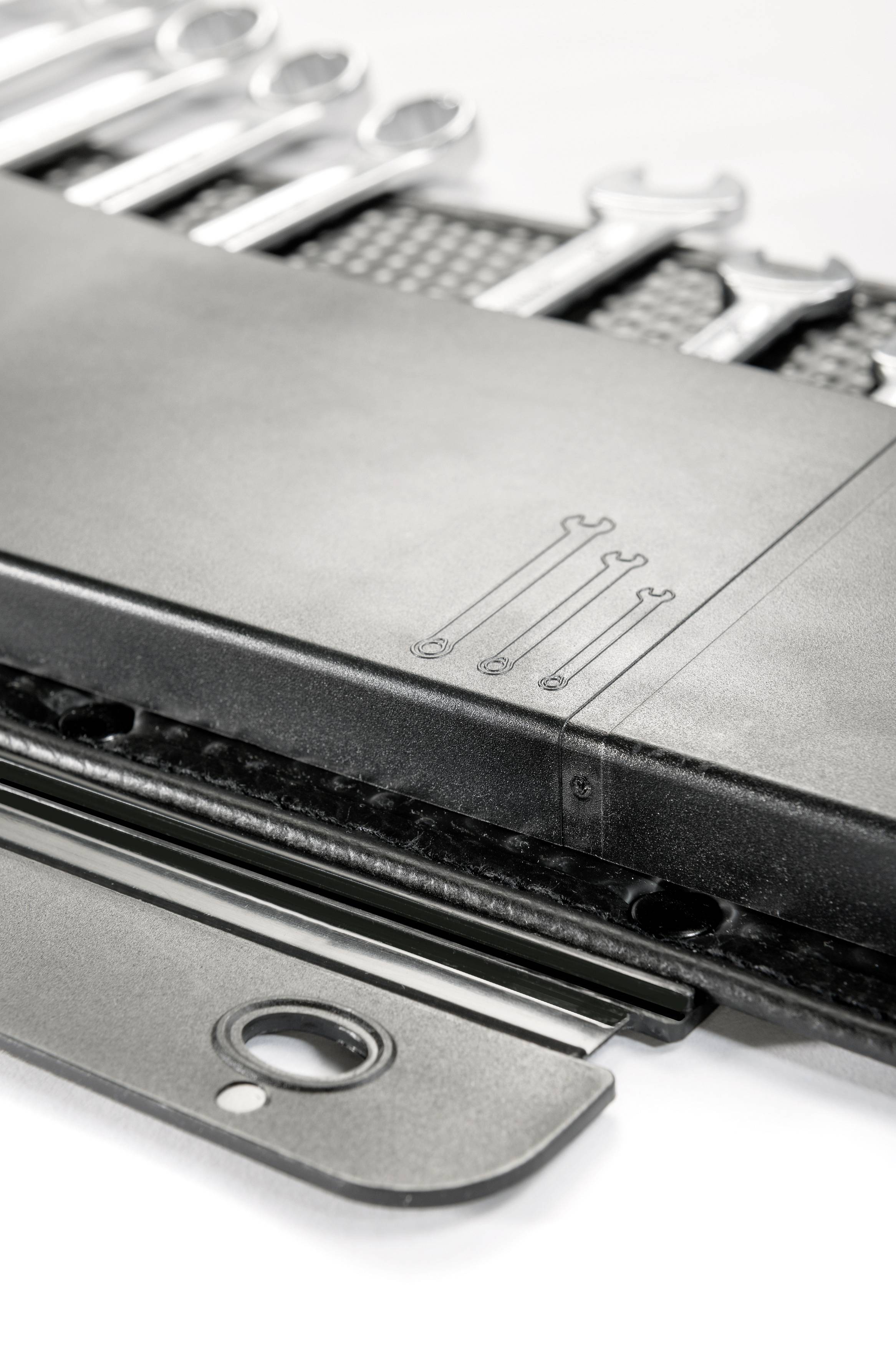 Stor metallåda med graverade skruvnycklar på, bredvid ligger en uppsättning skruvnycklar på ett svart invändigt foder.