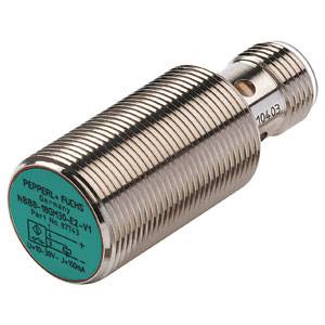 Cylindrisk sensor med metallhölje, tillverkarens tryck och tekniska specifikationer synliga på grönt etikett.
