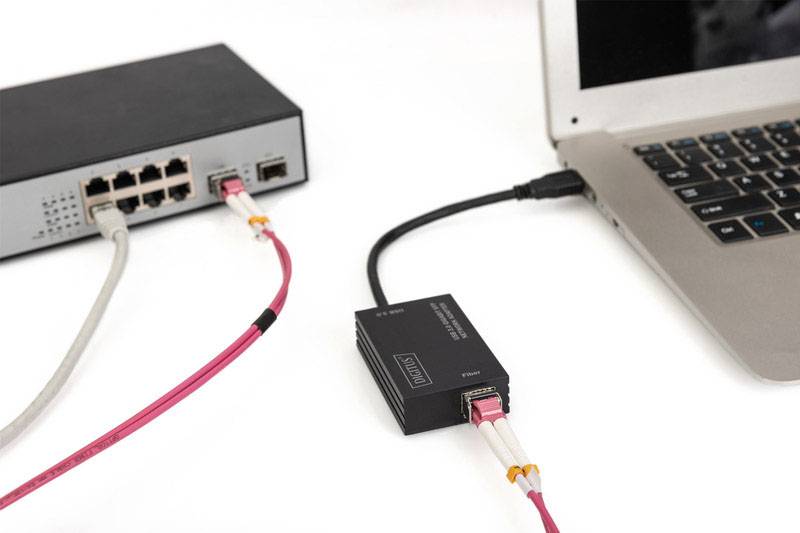 Bärbar dator ansluten till switch och nätverksadapter via kabel.