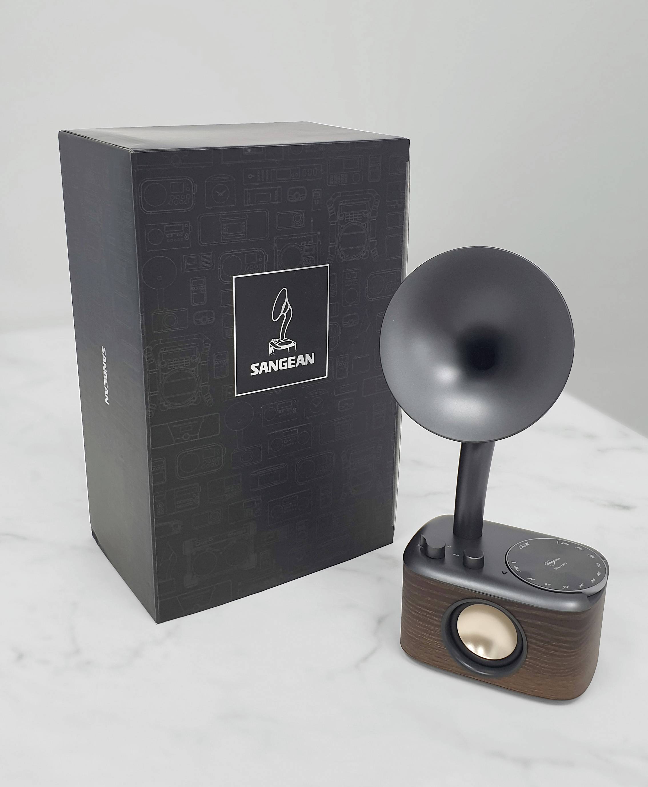 'Retrohögtalare och förpackningsbox. Högtalaren har en trädesign med ett trattformat horn och en stor volymreglage.'