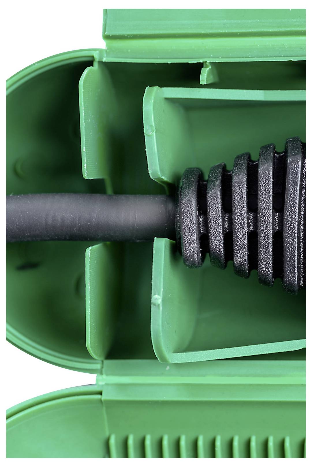 Närbild av ett grönt plastikkopplingshus med en svart kabel eller slang införd i mitten.