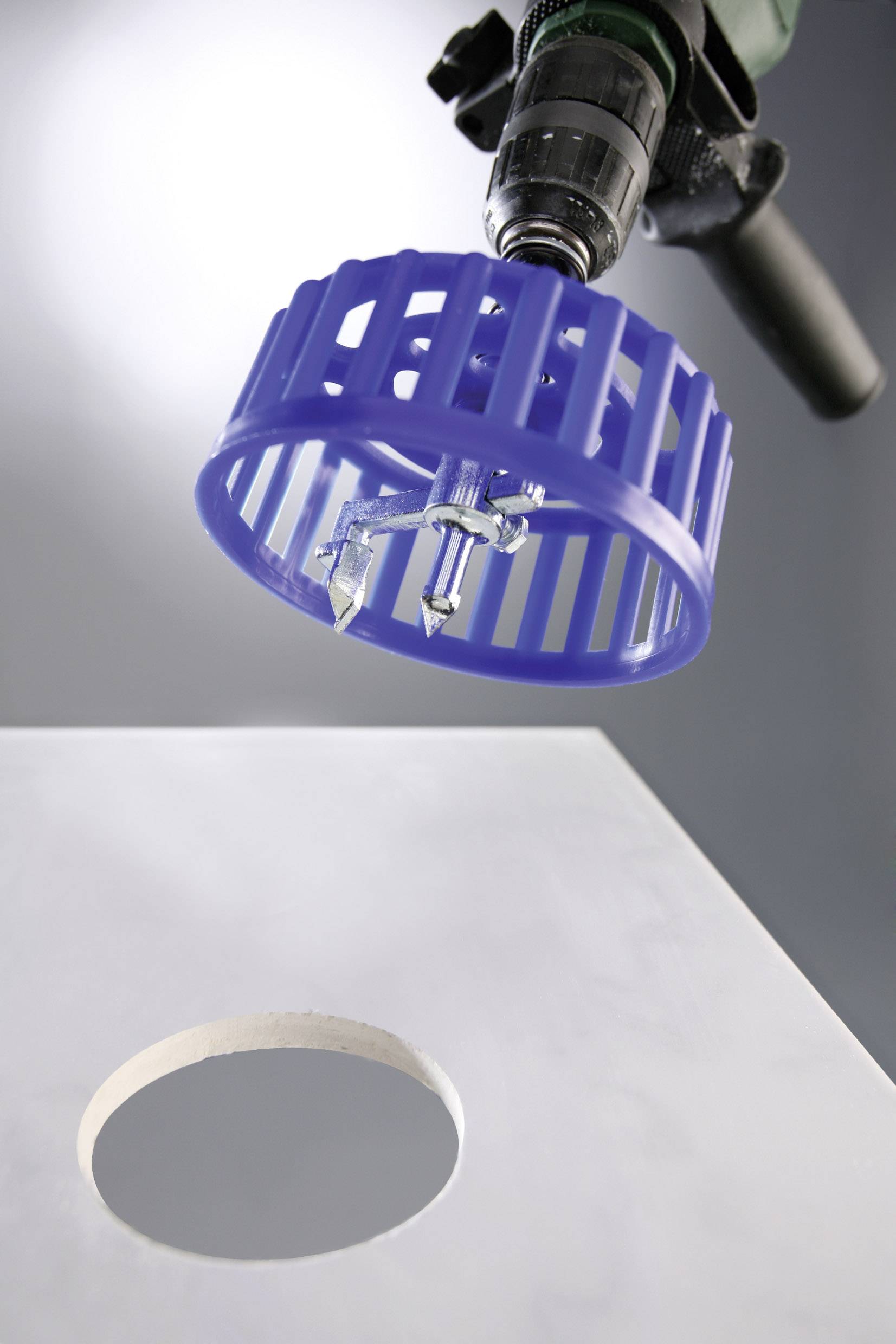 Borr med borrfästen, bredvid en slät vit platta med borrat hål.