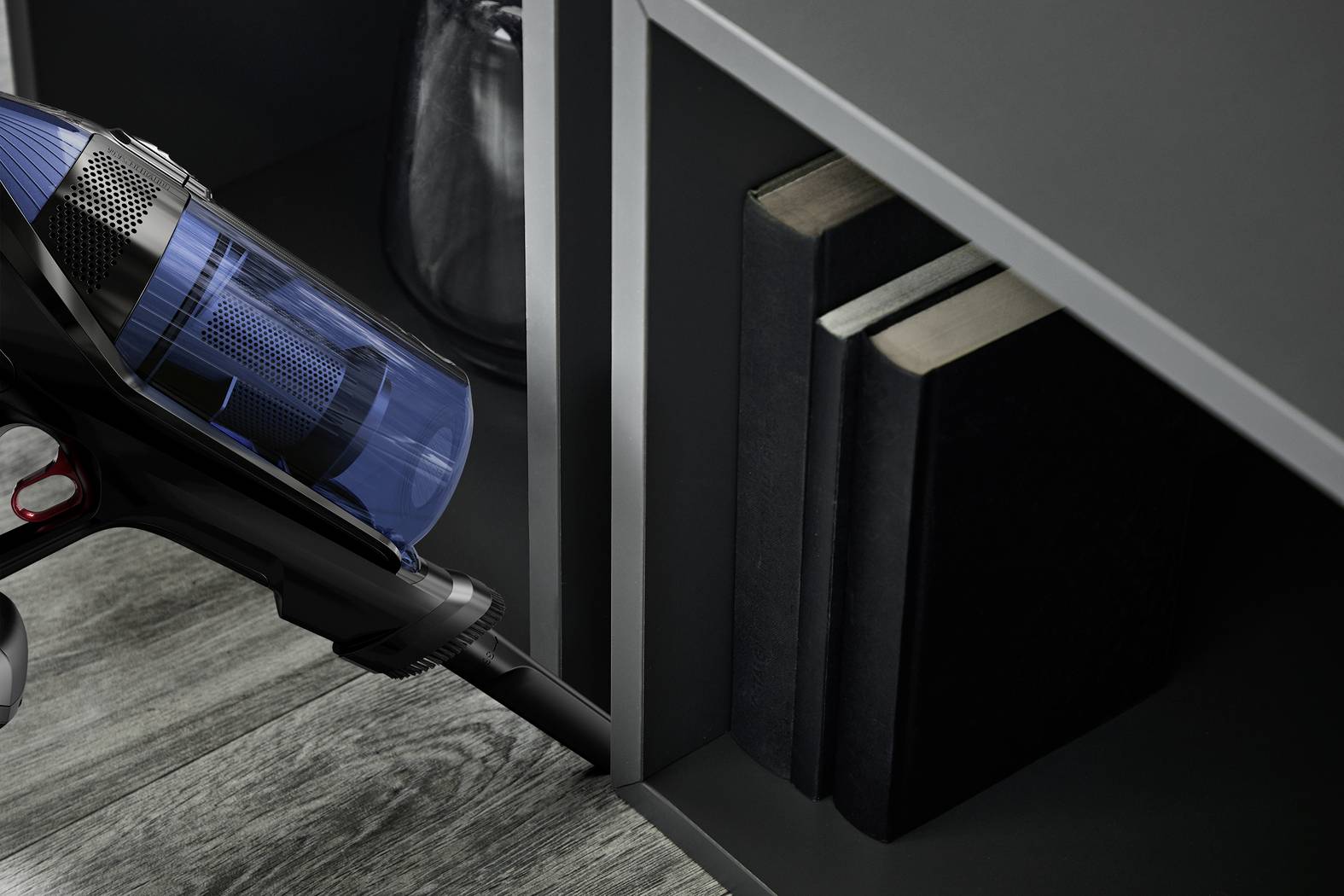 En handdammsugare rengör trånga mellanrum i bokhyllan.