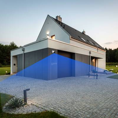 Ett modernt tvåvåningshus med blå säkerhetssensorvisning framför garaget, omgivet av en välskött trädgård och träd i bakgrunden.