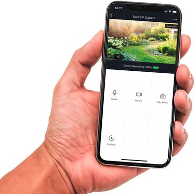 En hand håller en smartphone som visar en övervakningskamera-app. Skärmen visar en anslutning till kameran med 100% batteriladdning.