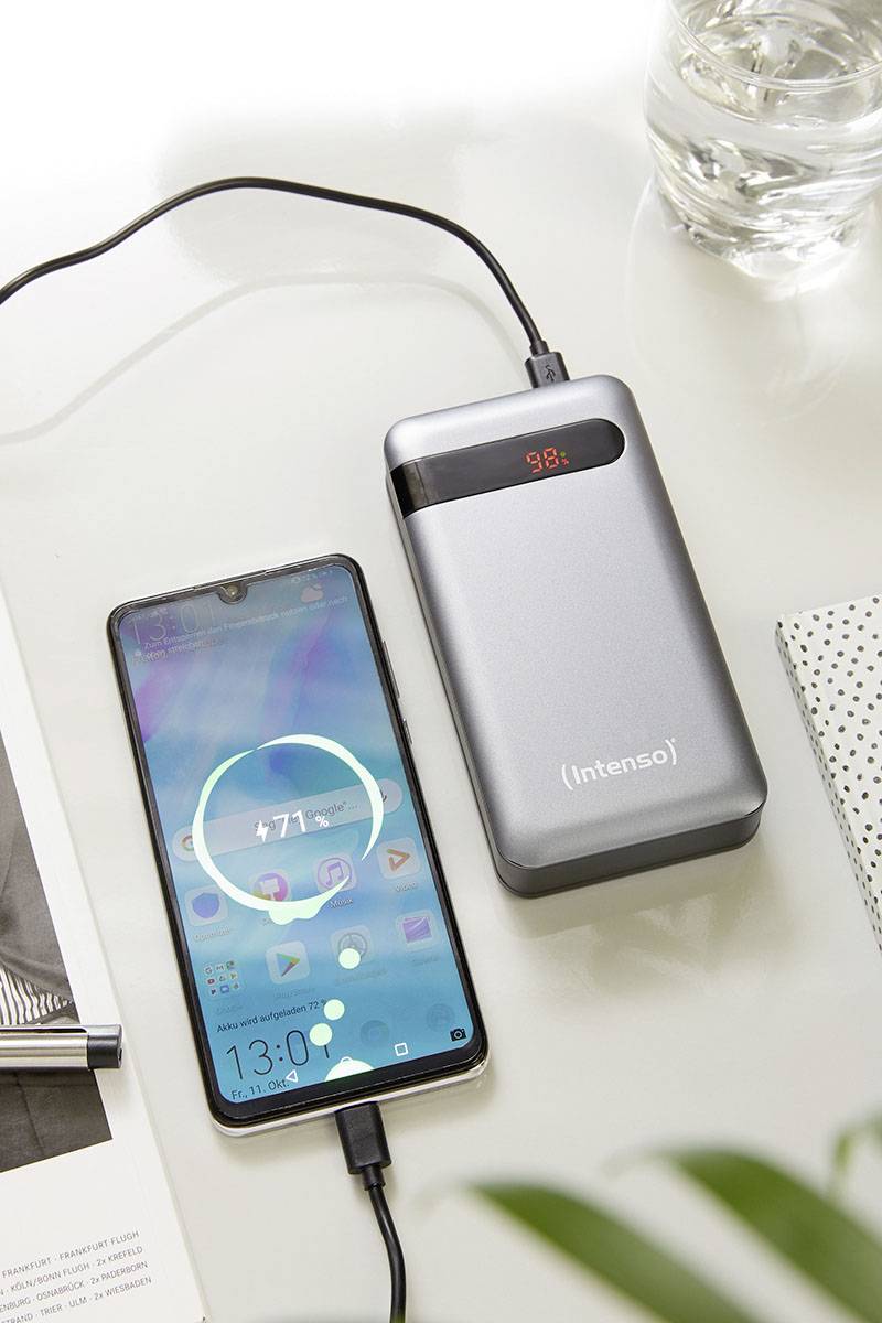 En smartphone laddas av en grå powerbank. På smartphonens skärm visas '71%'. Powerbankens display visar '98%'.