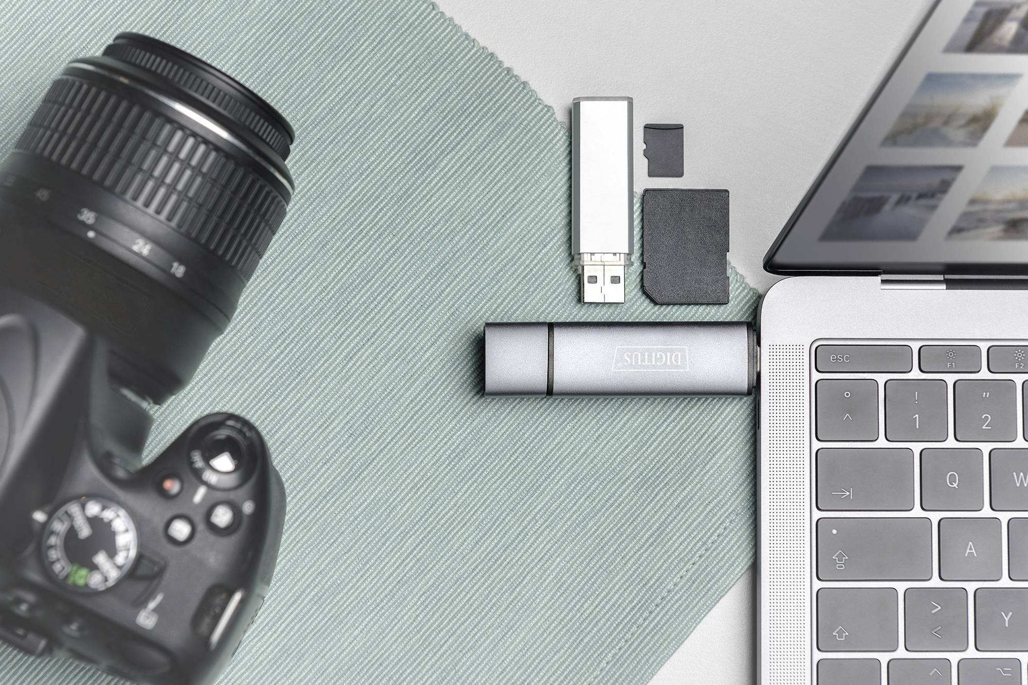 Bärbar dator med foton på skärmen, bredvid kamera och USB-sticka. Tema: digital fotografering och datalagring.