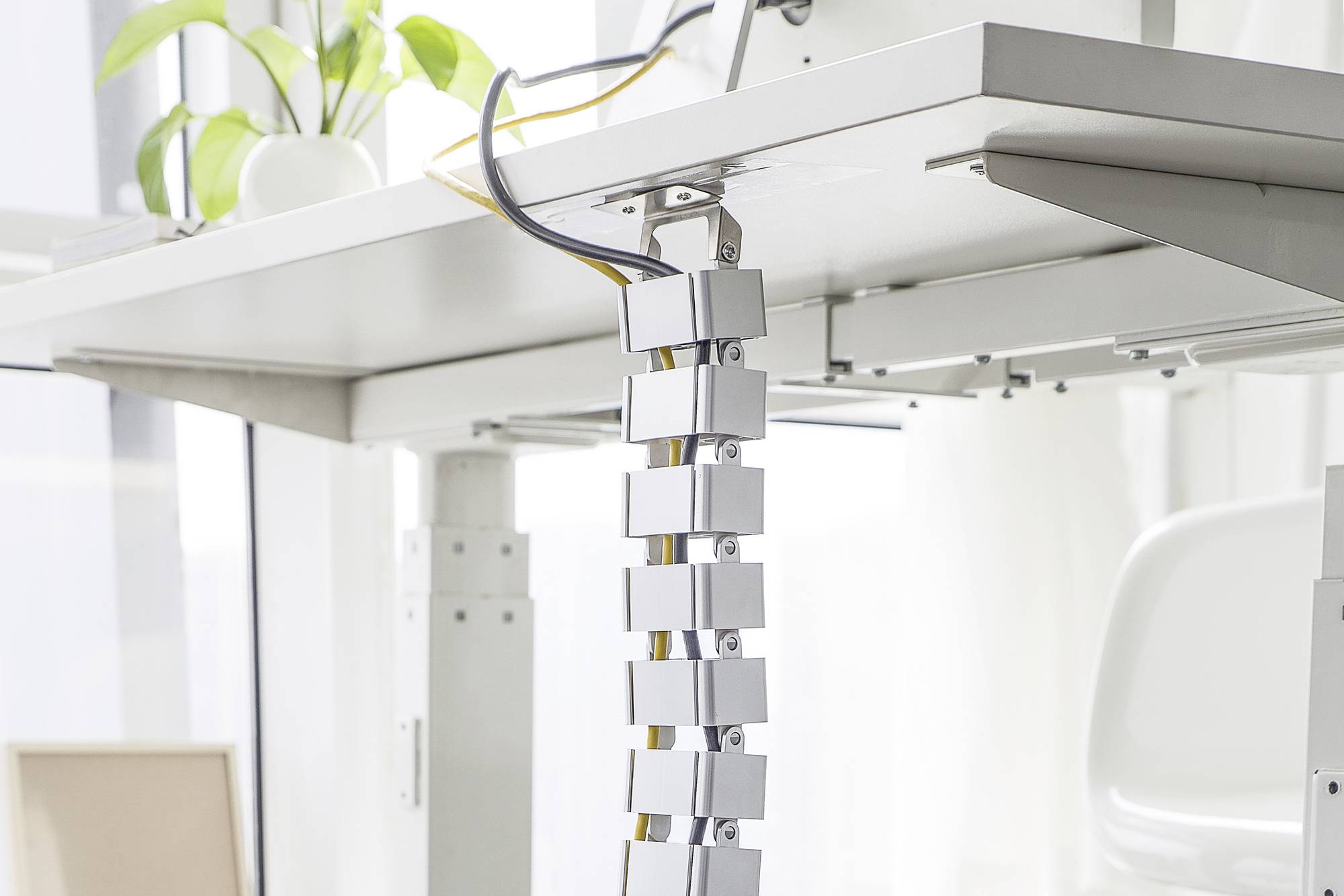 Ett skrivbordskabelstyrsystem som visar flexibla kabelclips för att organisera kablar snyggt under ett skrivbord.