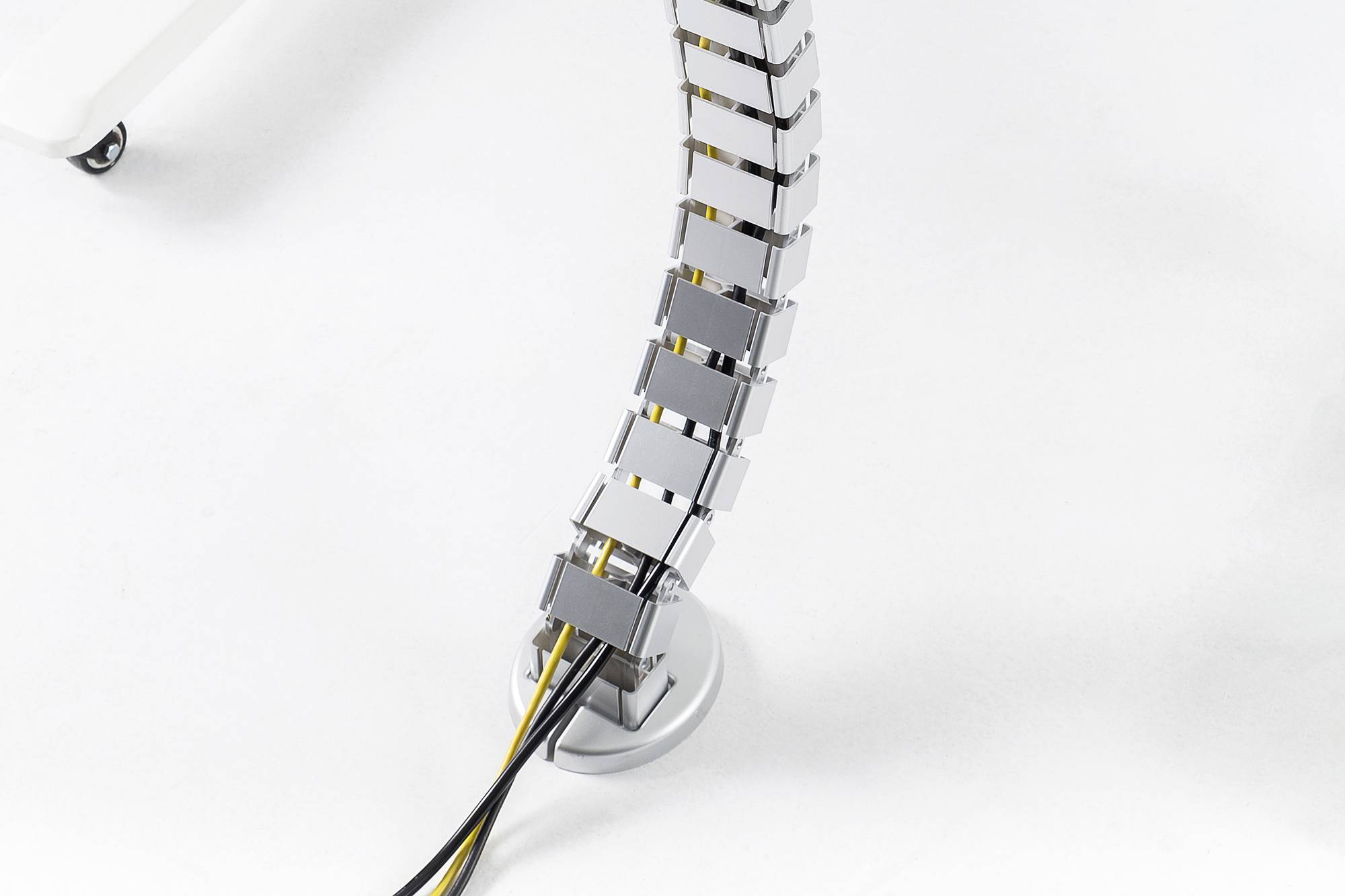 En flexibel kabelstativ med justerbara segment som sträcker sig från ett skrivbord ner till golvet och leder svarta och gula kablar.