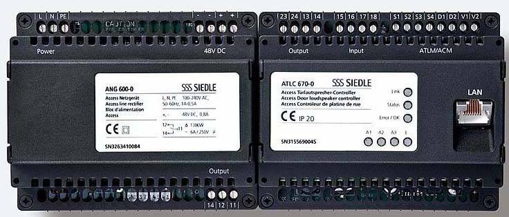 Två svarta elektroniska styrsystem bredvid varandra, var och en med flera anslutningar. Till vänster 'ANG 600-0', till höger 'ATLC 670-0', LAN-anslutning till höger.