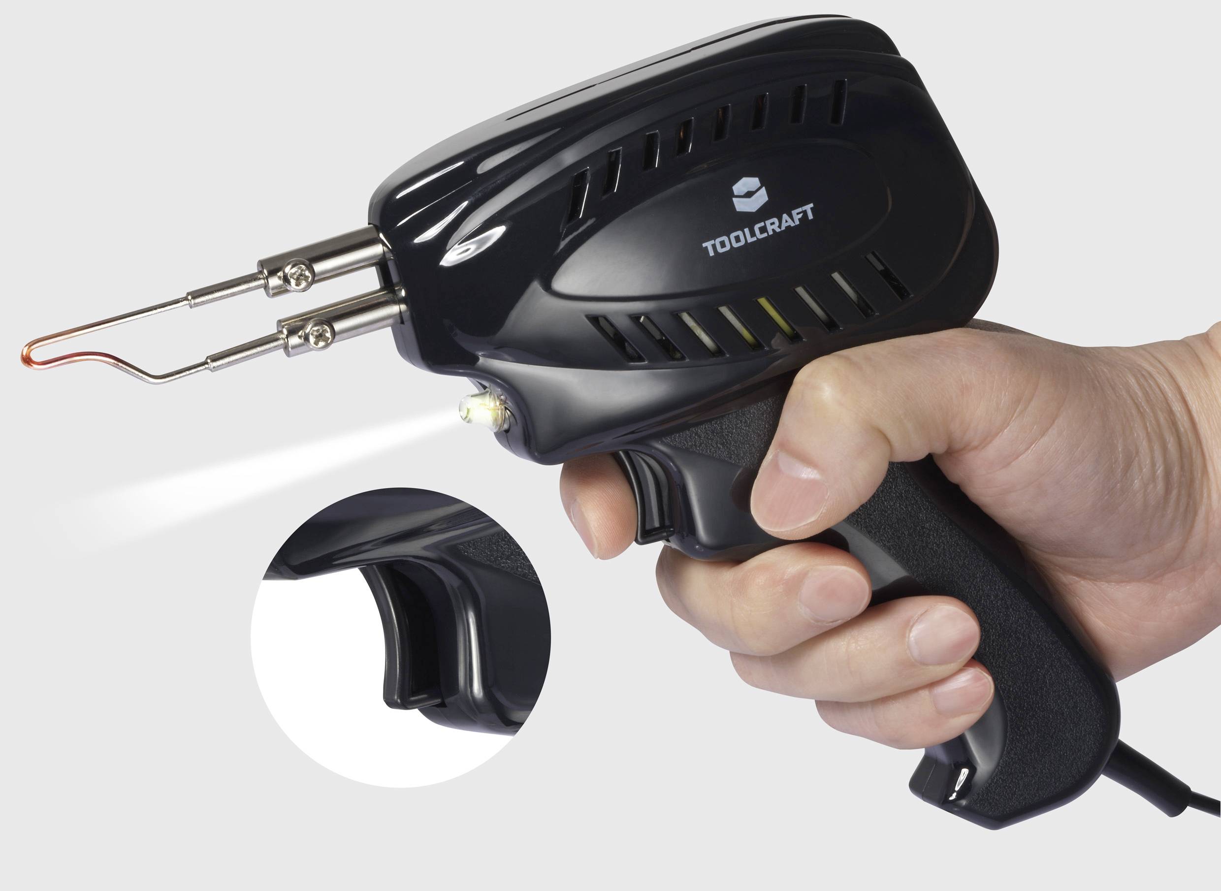 En hand håller en elektrisk lödpistol från märket TOOLCRAFT. Spetsen på pistolen är het och lyser röd.
