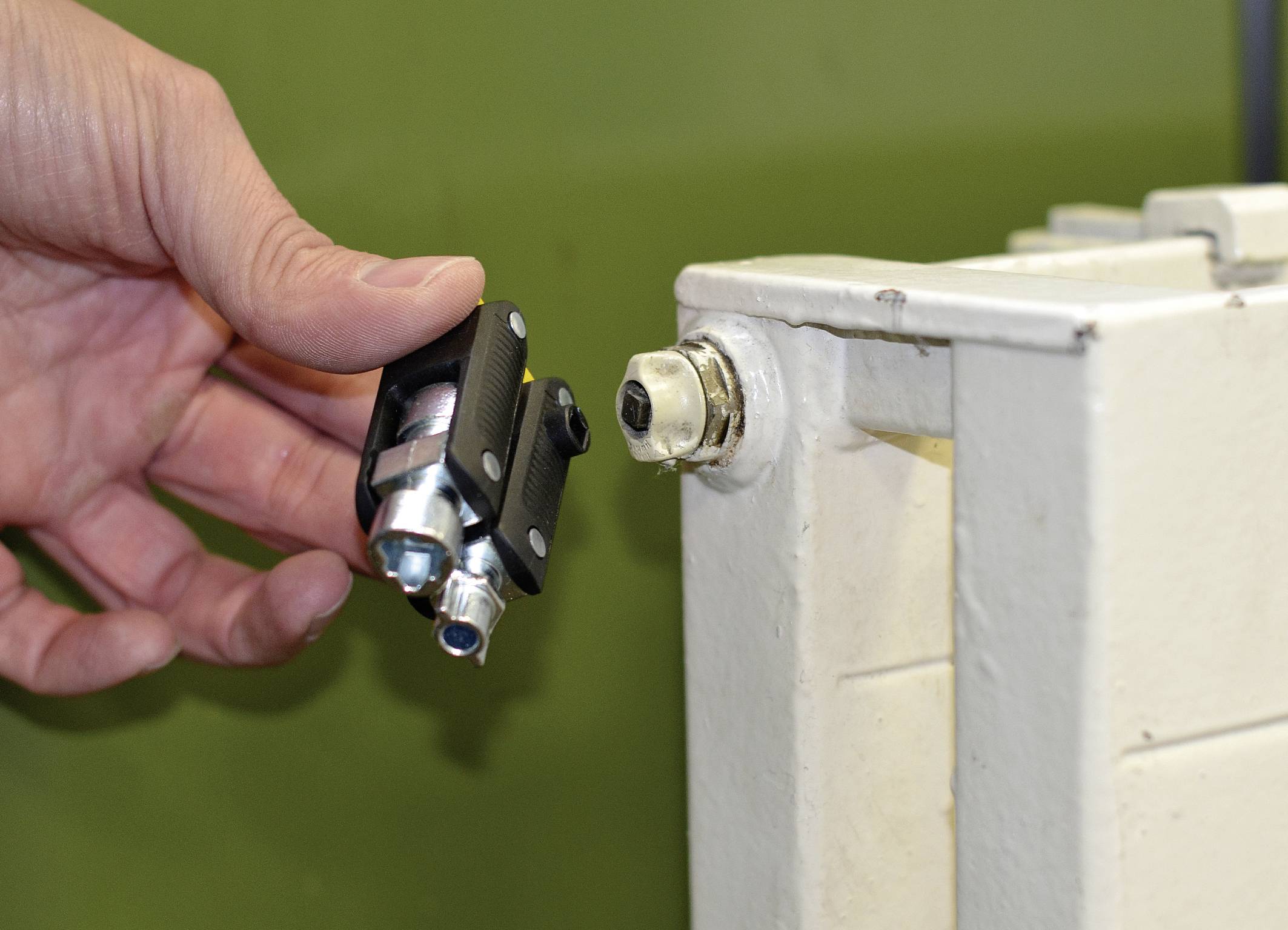 En hand håller ett infraröd-termometer framför en värmeanslutning.