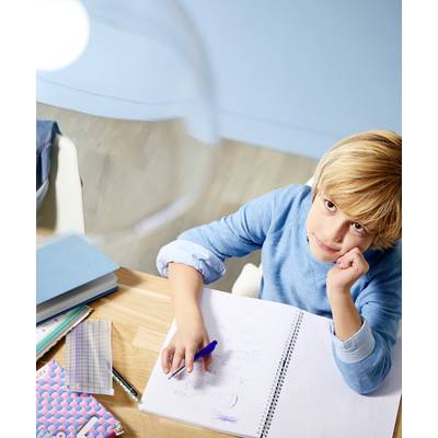 Ett barn sitter vid bordet och tittar tankfullt på en öppen anteckningsbok. På bordet ligger skrivmaterial och skolmateriel.