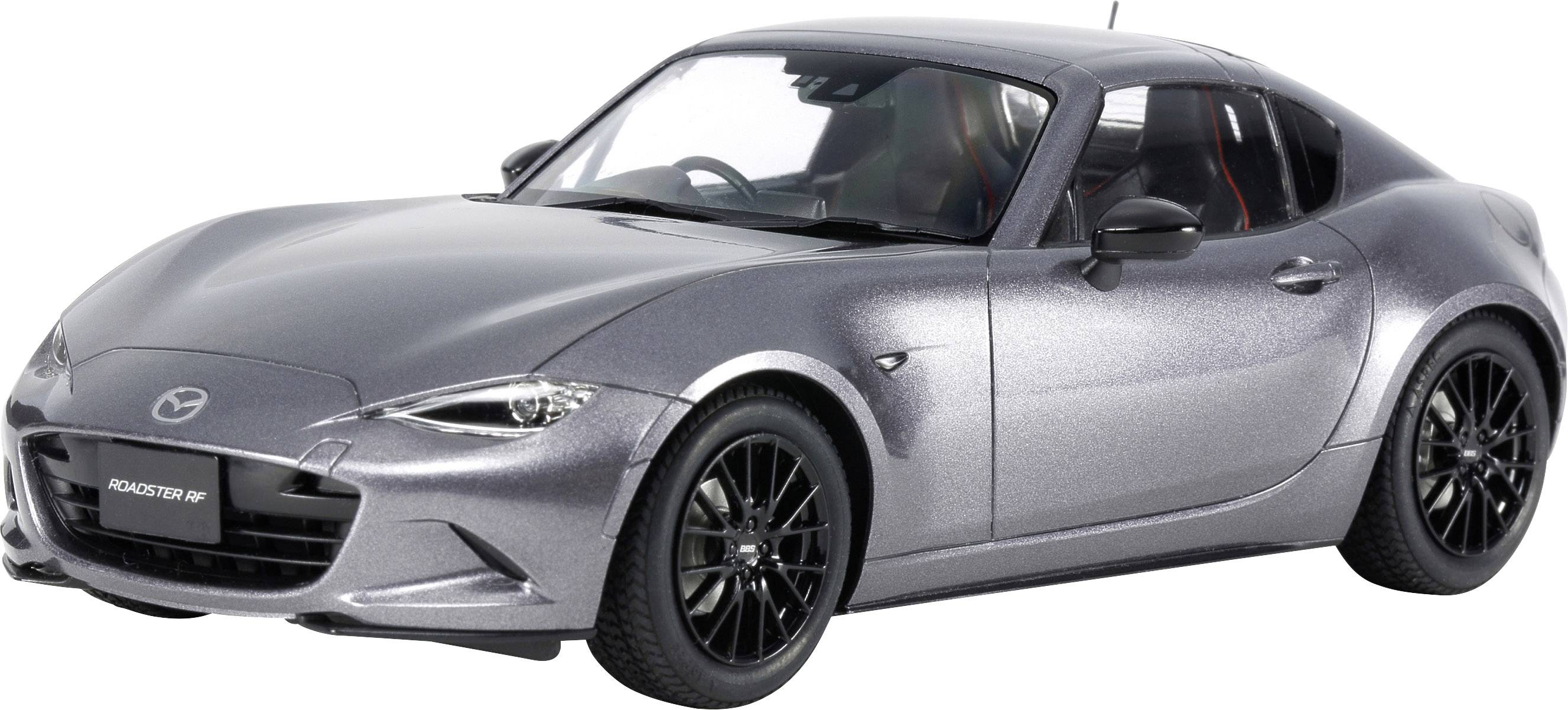 Ett silvergrått sportcoupé på grå bakgrund, fokuserat på fordonets vänstra sida; visar modernt design och aerodynamik.