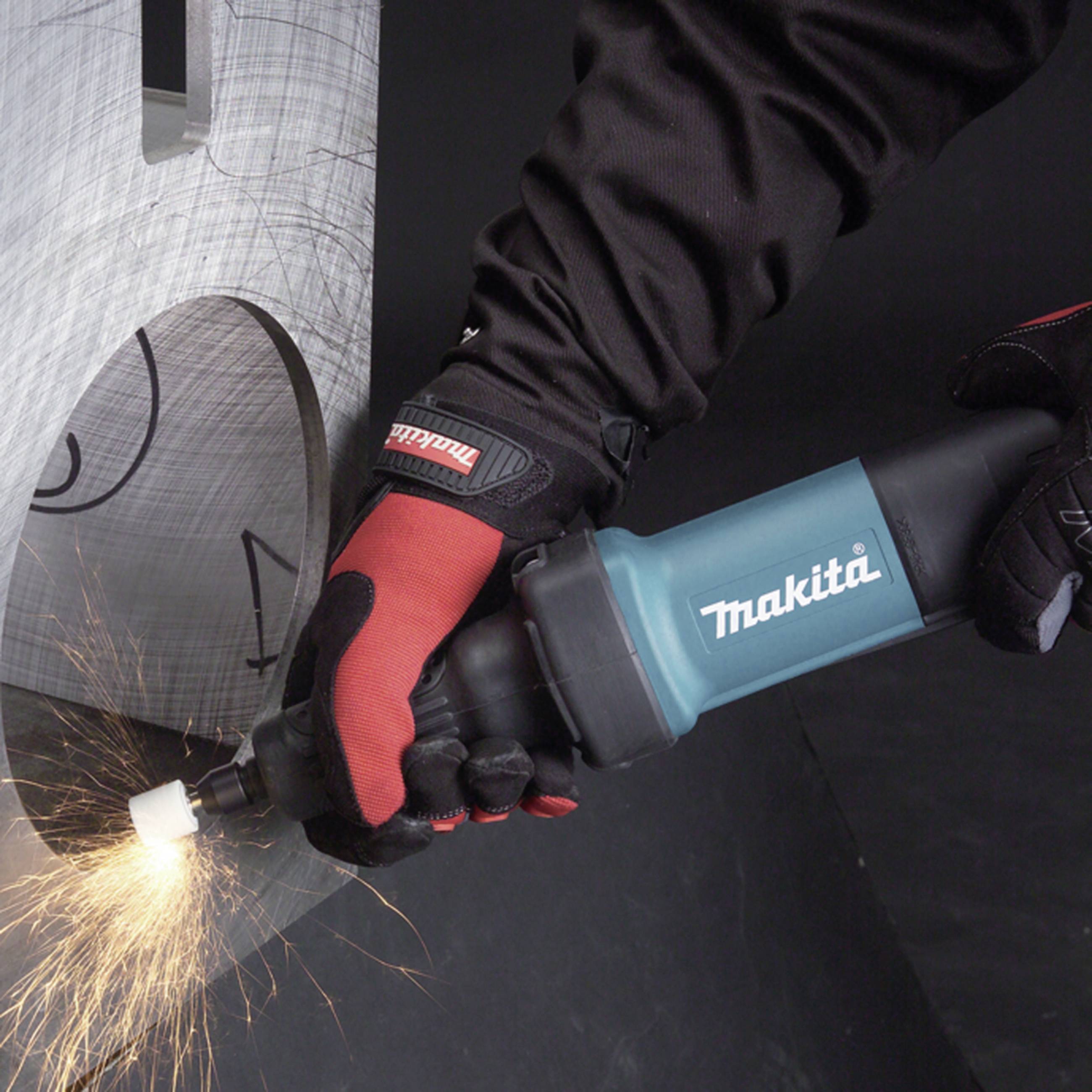 En person sliper metall med ett blått Makita-verktyg. Gnistor flyger medan slipningen pågår.