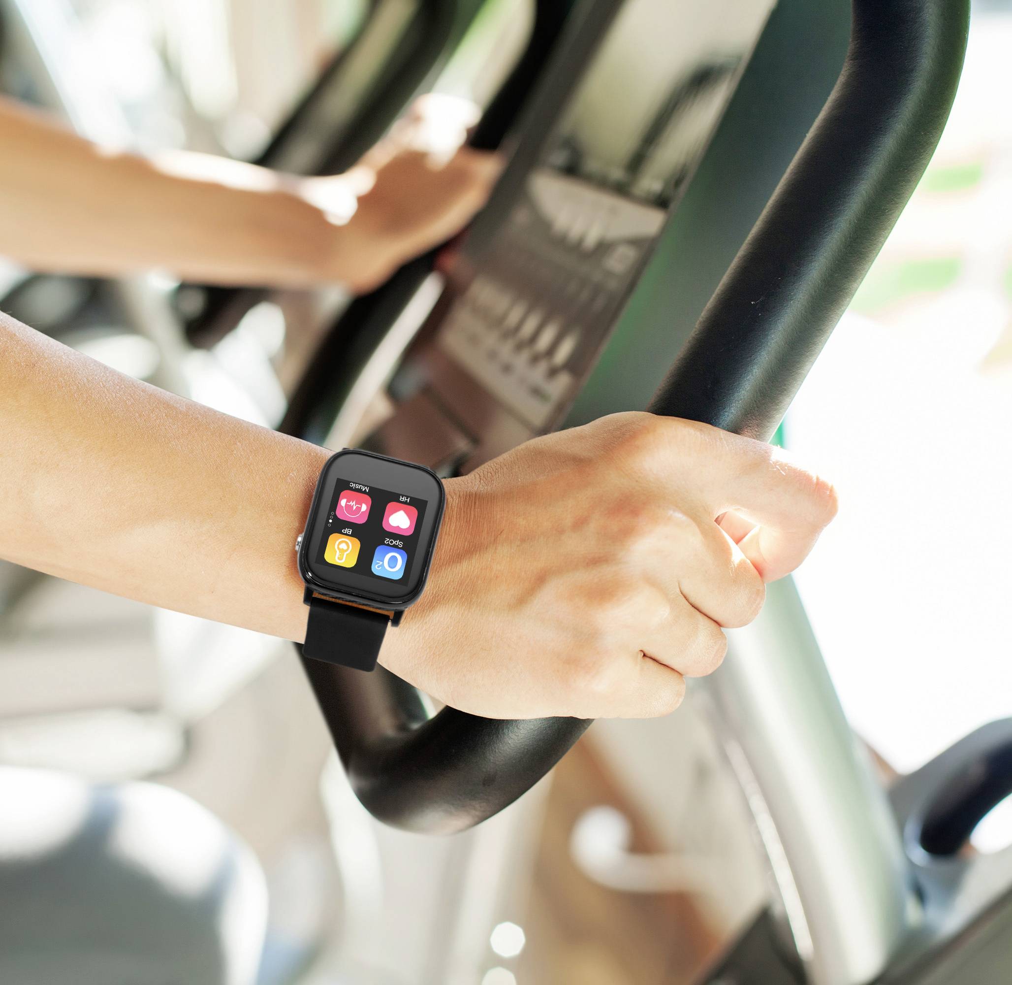 En person tränar på ett träningsredskap och bär en smartwatch på handleden som visar färgglada appar på displayen.