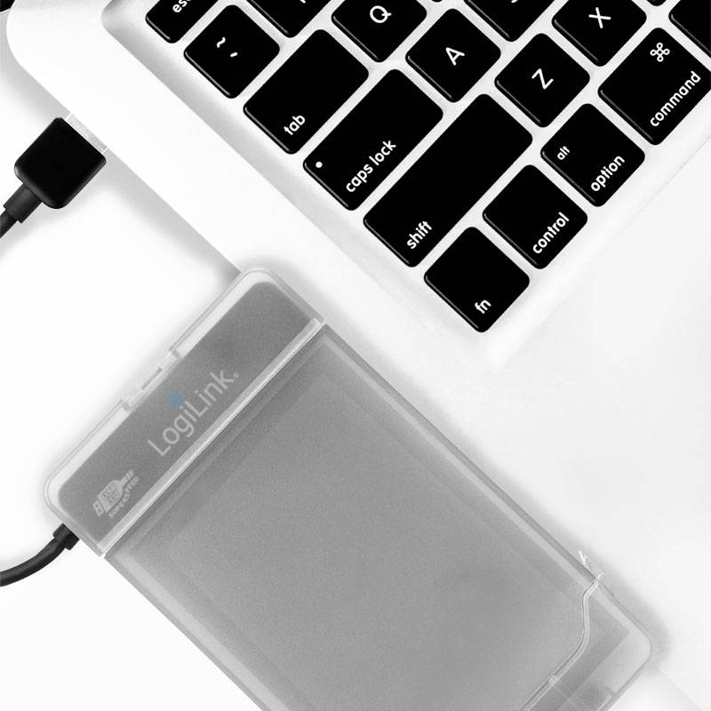 Extern hårddisk ansluten till en bärbar dator via en USB-kabel, placerad på en vit yta.