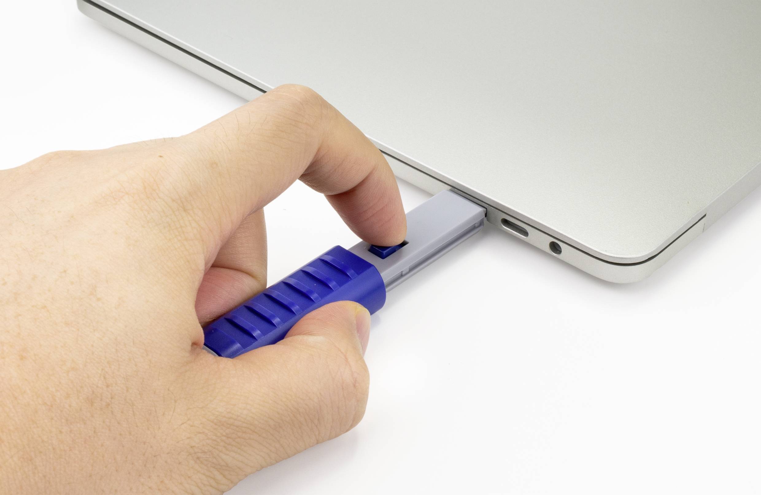 En hand stoppar in ett blått USB-minne i en bärbar dator.