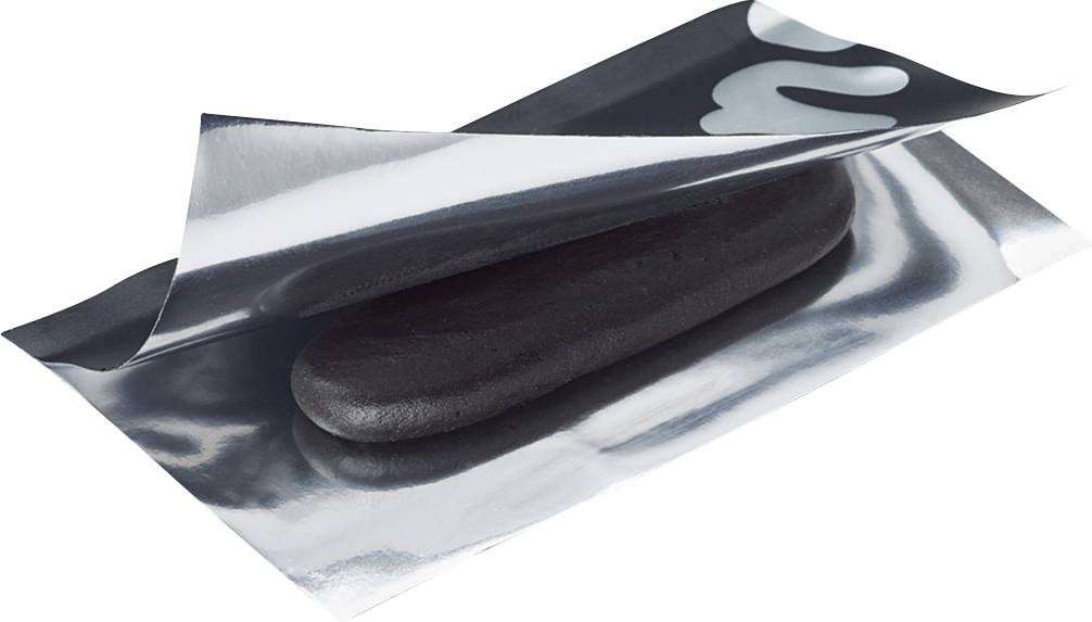 Ett svart mjukdegsstycke ligger på ett blankt metallpapper, delvis täckt.