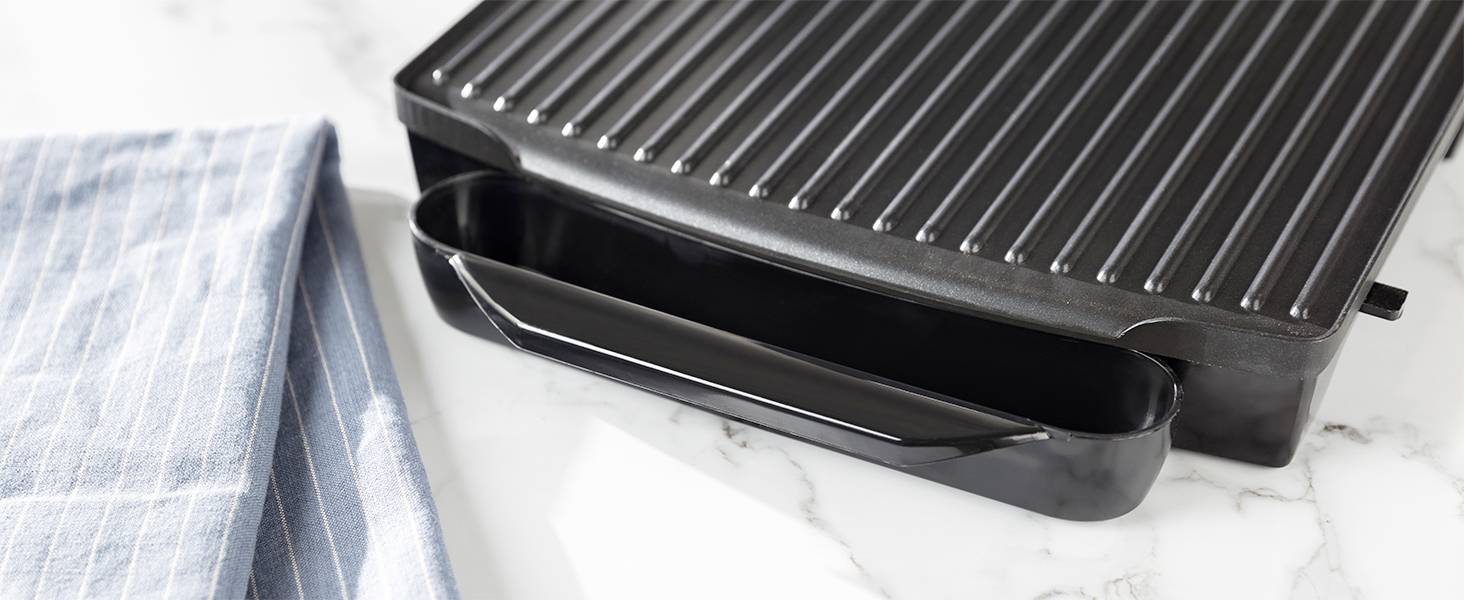 Svart grillplatta på en vit marmoryta bredvid en ljusblå, randig kökshandduk.