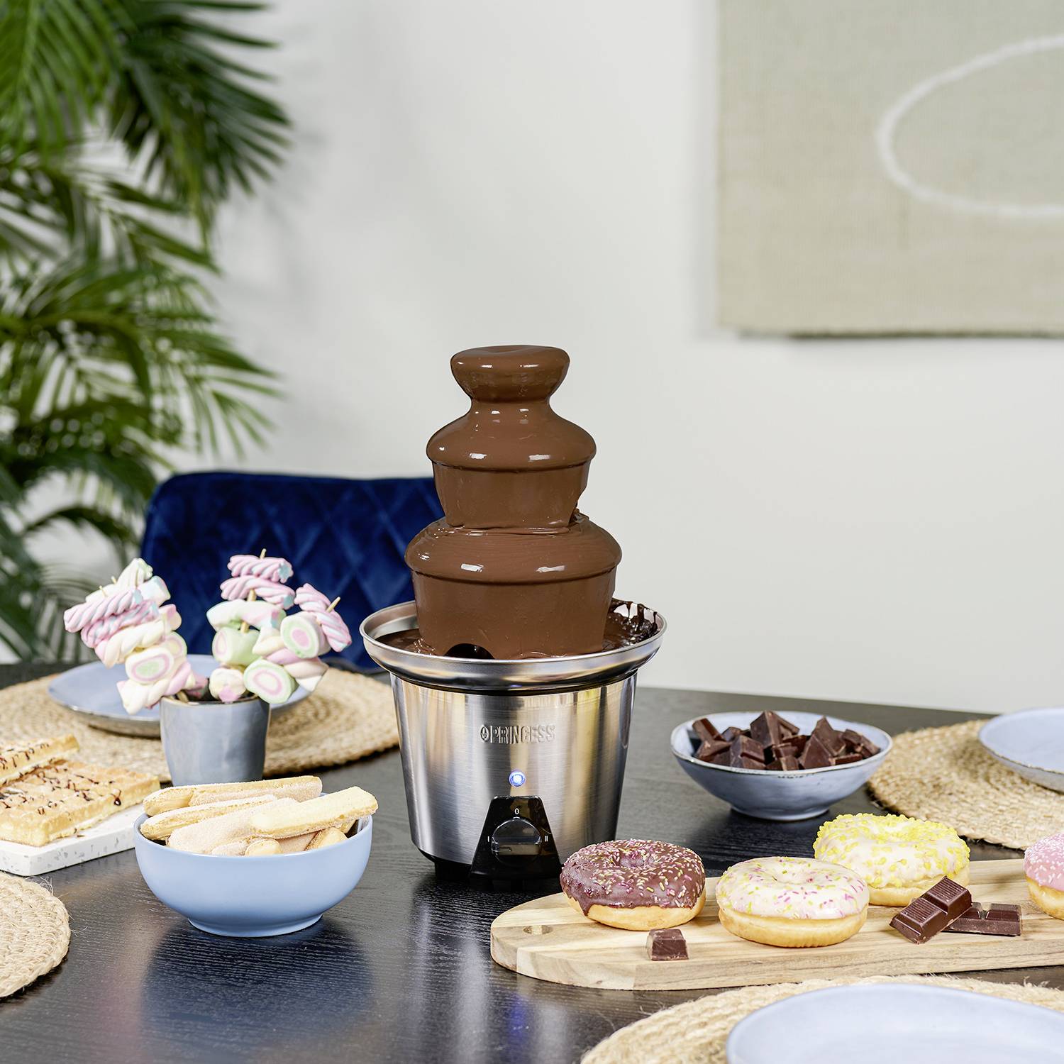 Chokladfontän med tilltugg: Frukt, bakverk och färgglada godsaker ligger redo på ett bord för att doppas i chokladflödet.