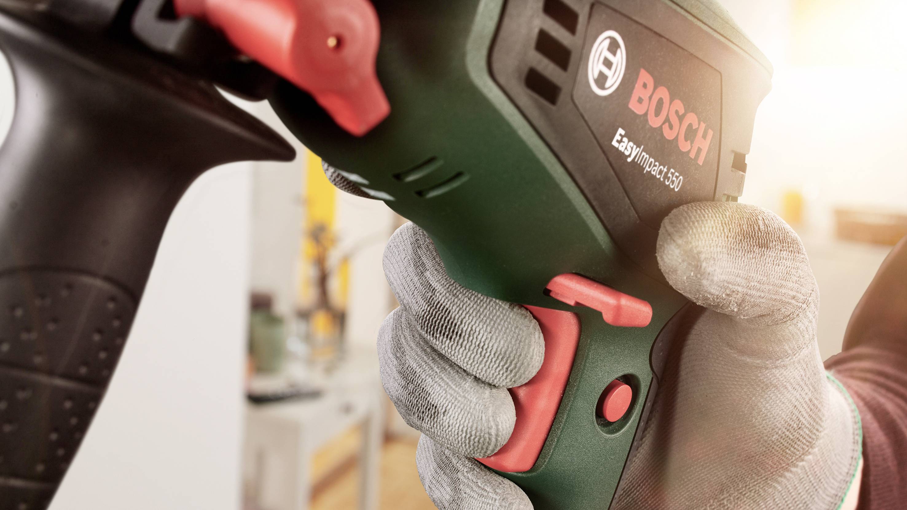 En person håller i en grön Bosch slagborrskruvdragare. Texten 'EasyImpact 550' är synlig.