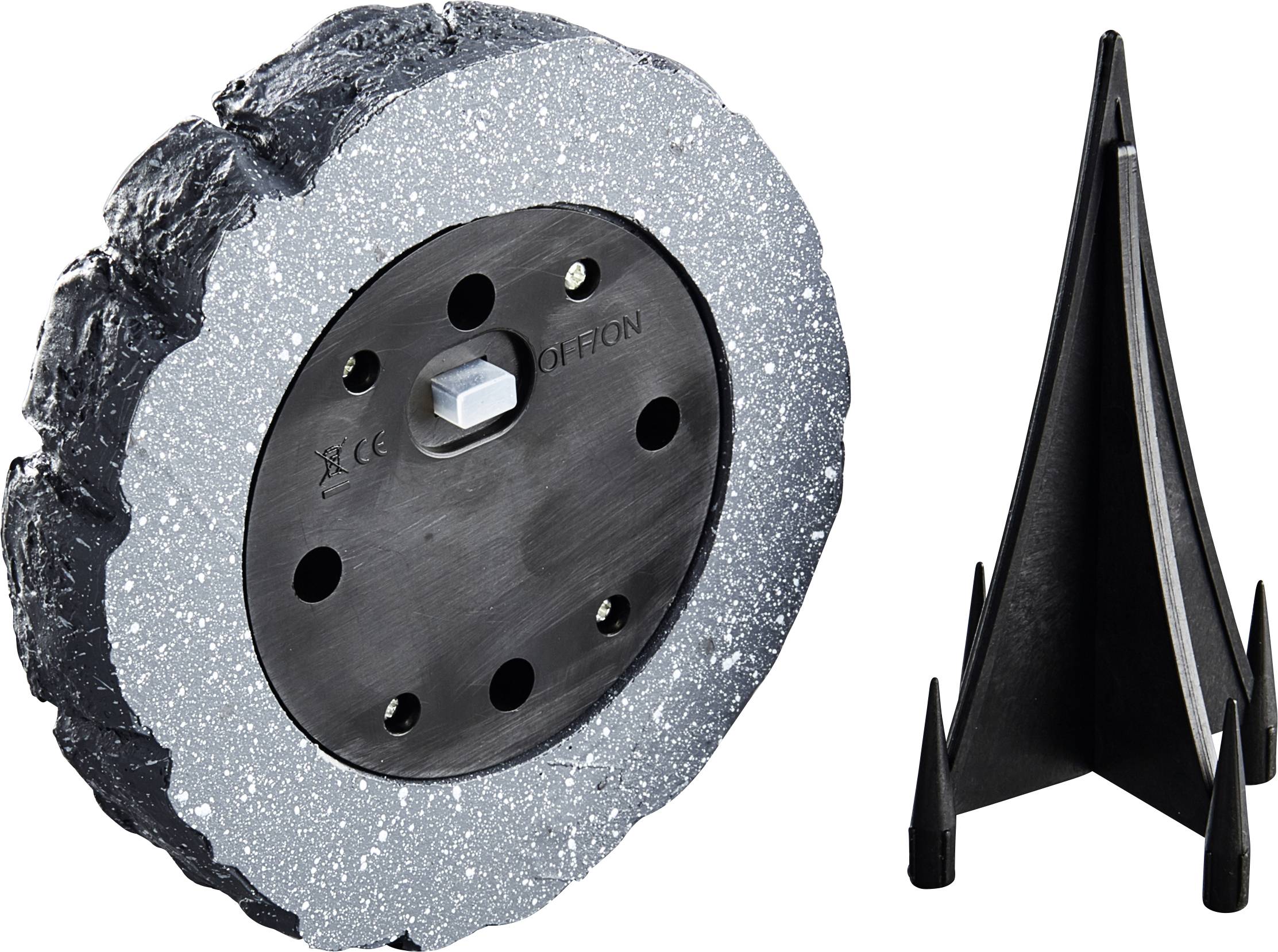 'Rund, grå och svart bas med metallkontaktpunkter, bredvid ett svart, stelt stativ med tre pinnar. Komponenter till en bordsfot.'