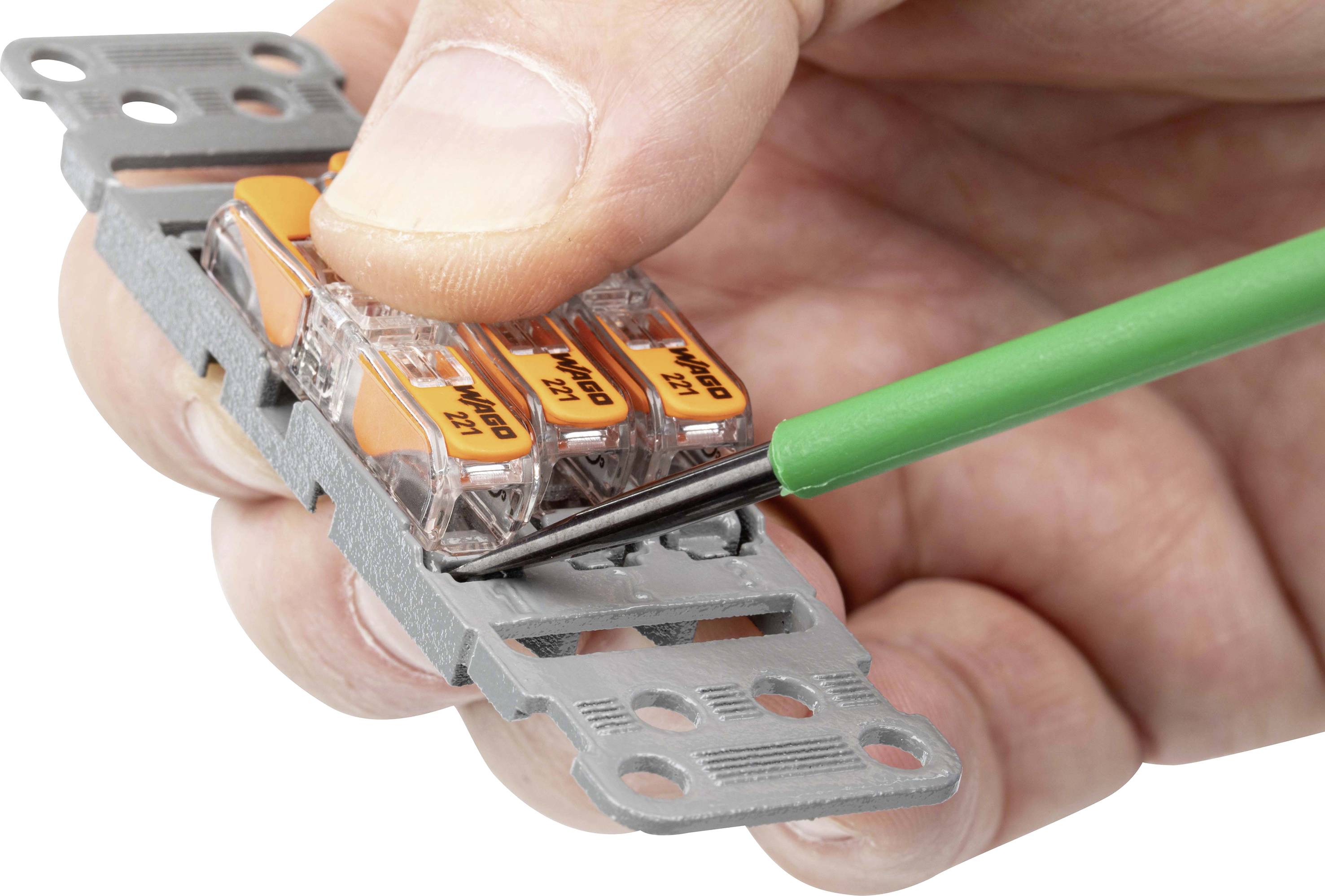 En skruvmejsel används för att lossa en Wago-kopplingsklämma som hålls i handen.