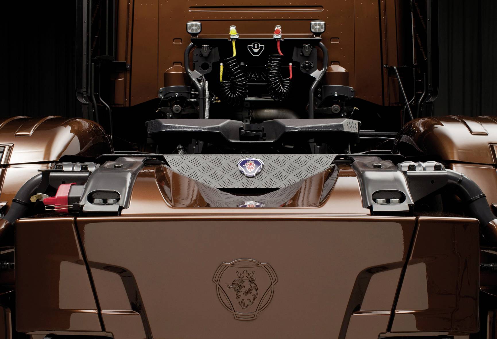 Brun lastbil sedd bakifrån, visar kopplingen och luftanslutningarna i rött, gult och svart med en logotyp i mitten.