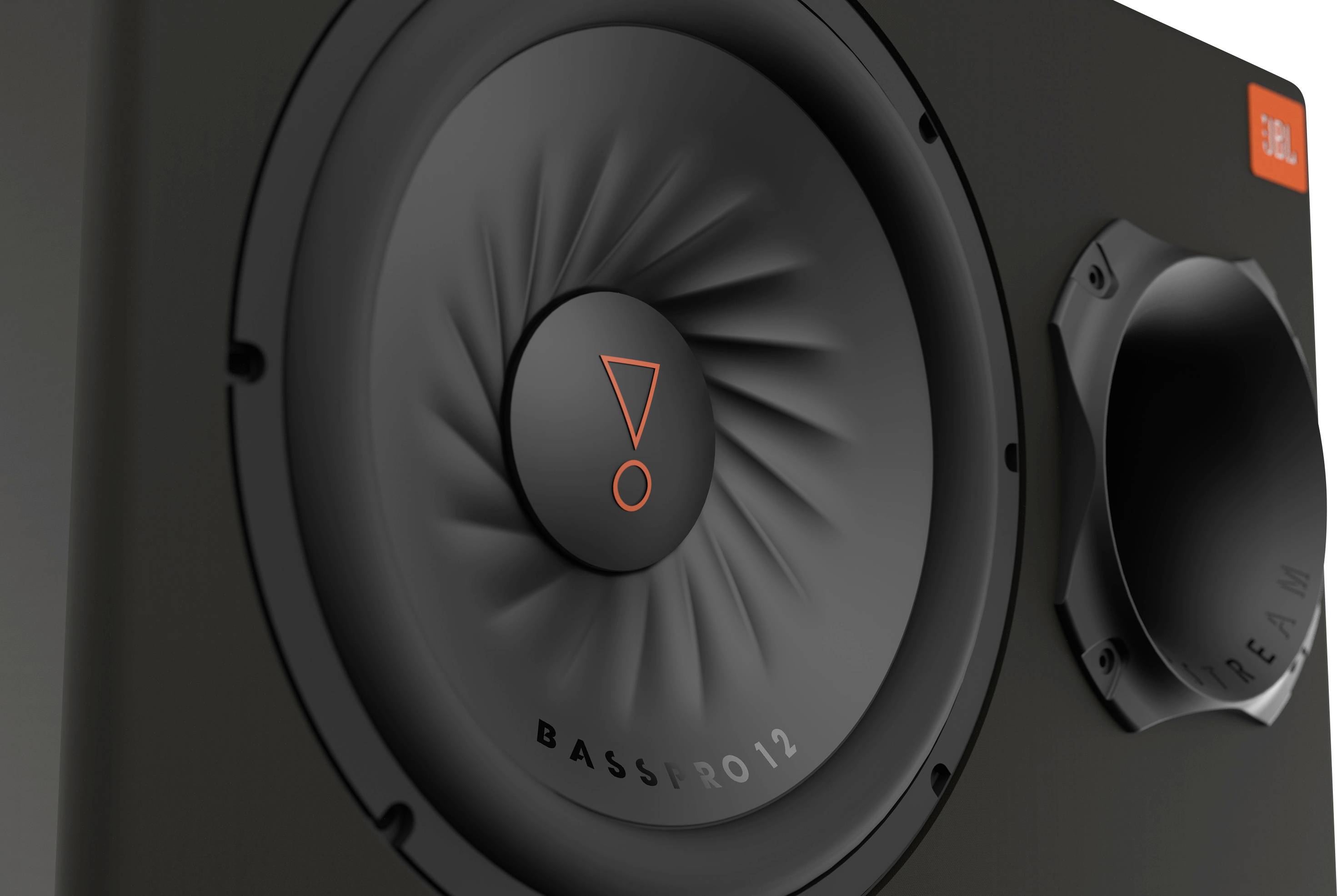 Närbild av en svart högtalare med orange logotyp och texten 'BASSPRO12'. En ljudöppning synlig till vänster.