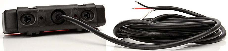 Svart backkamera med två linser och långt anslutningskabel, placerad på en reflekterande yta.