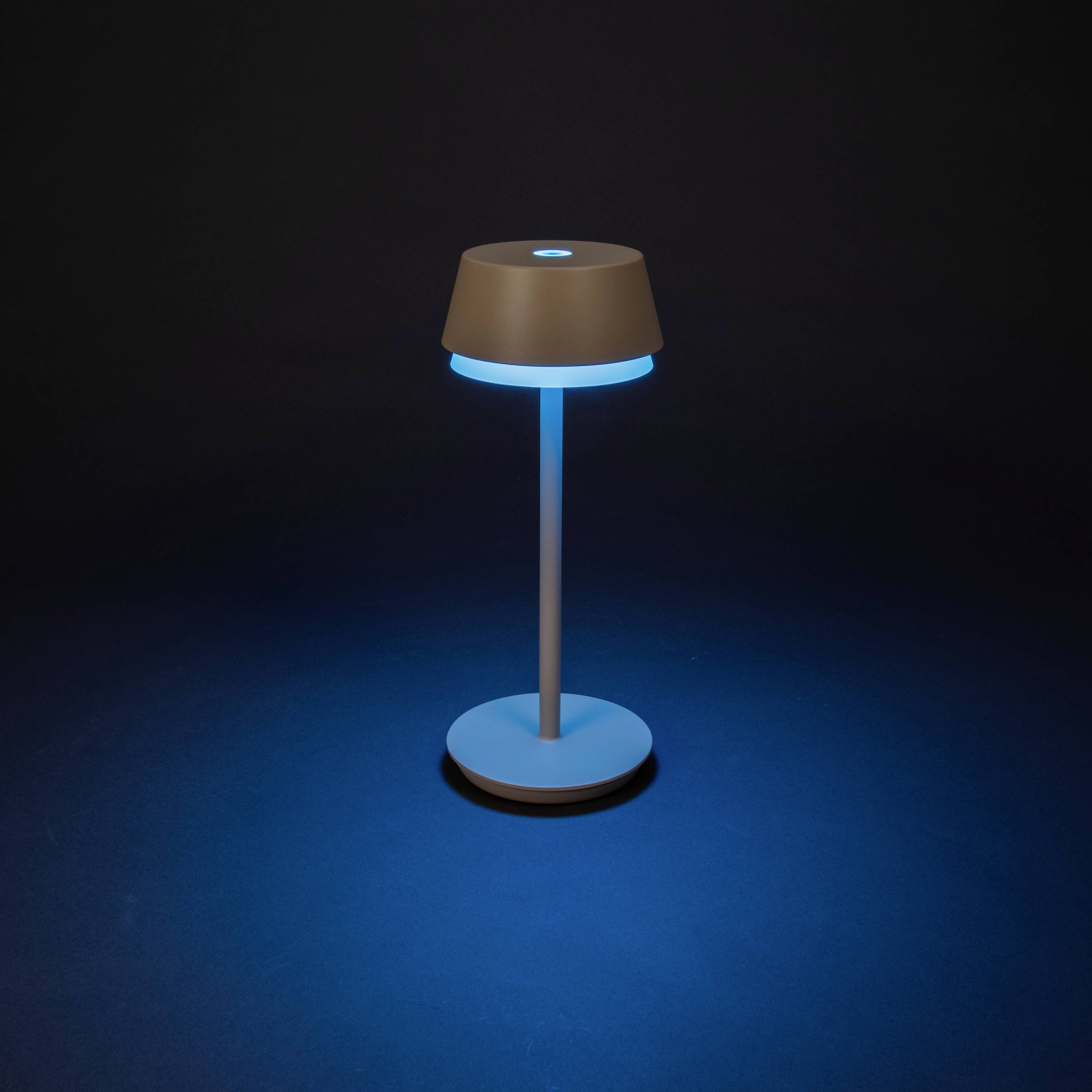 En modern bordslampa med enkelt design lyser med blått ljus och står mot en mörk bakgrund.