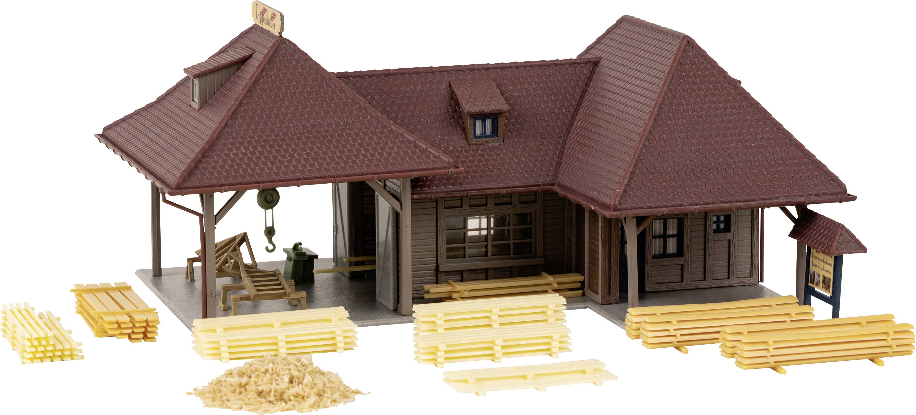 Miniatyrmodell av en lantlig järnvägsstation med vedstaplar i förgrunden. Byggnaden har ett tegeltak, skjul och vedhögar.