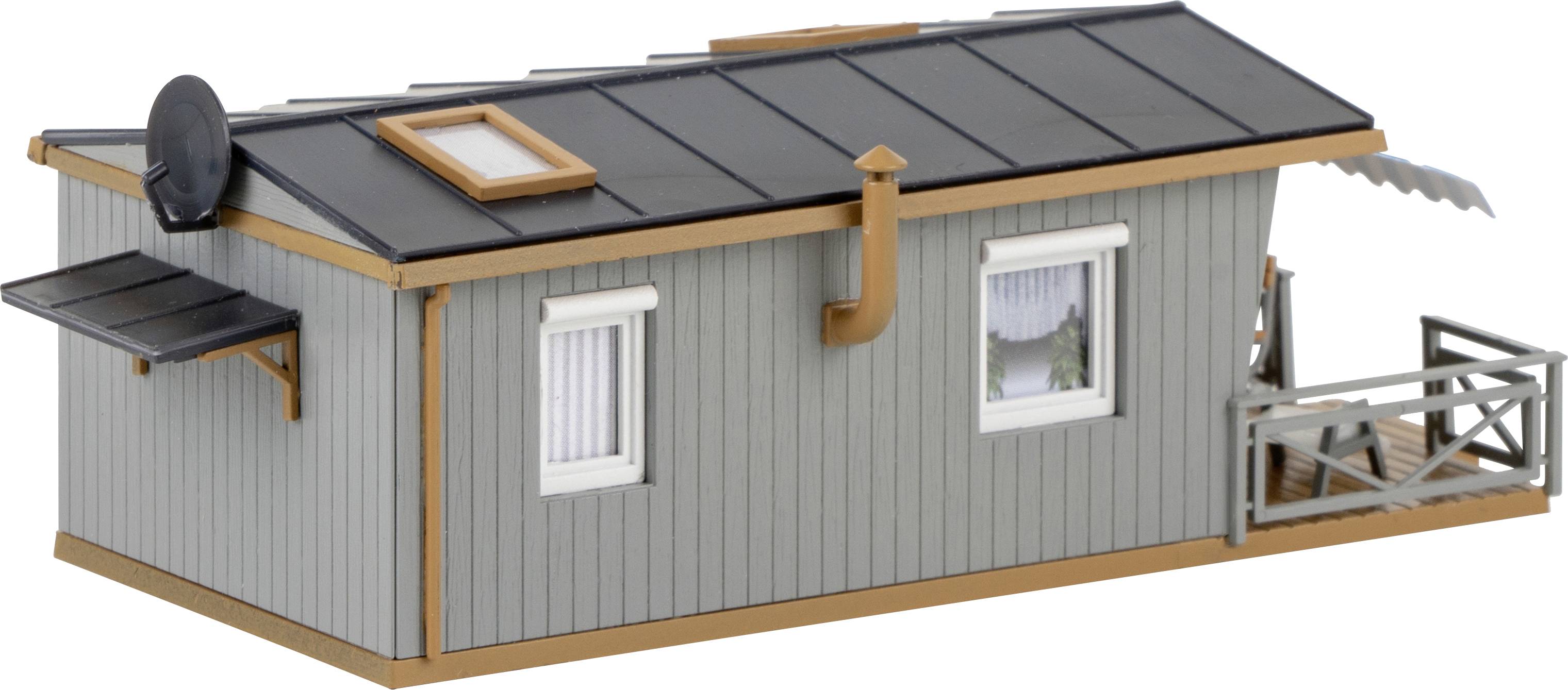 En grå modell av en liten byggnad med platt tak, parabolantenn och fönster. Till vänster en markis, till höger en liten balkong.