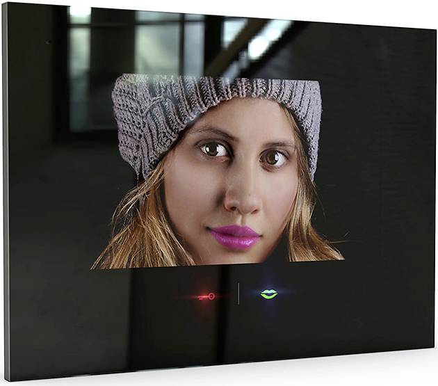 Ett foto visar ansiktet på en kvinna med en grå mössa och ett lätt leende. Bakgrunden är mörk och oskarp.