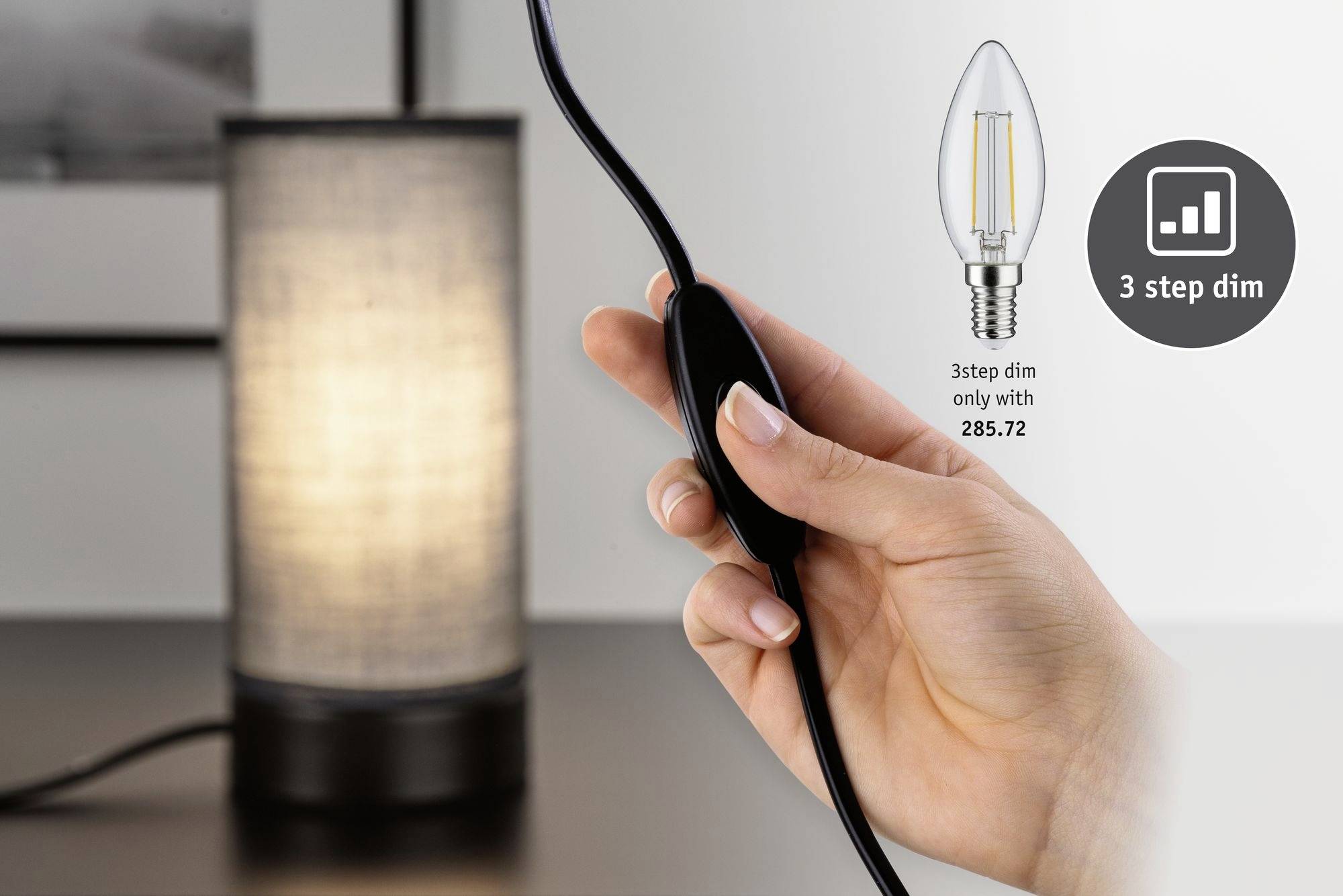 En hand håller en dimmer stående. Bredvid finns en bordslampa, en glödlampsbild och en symbol med texten "3-stegs dimning".