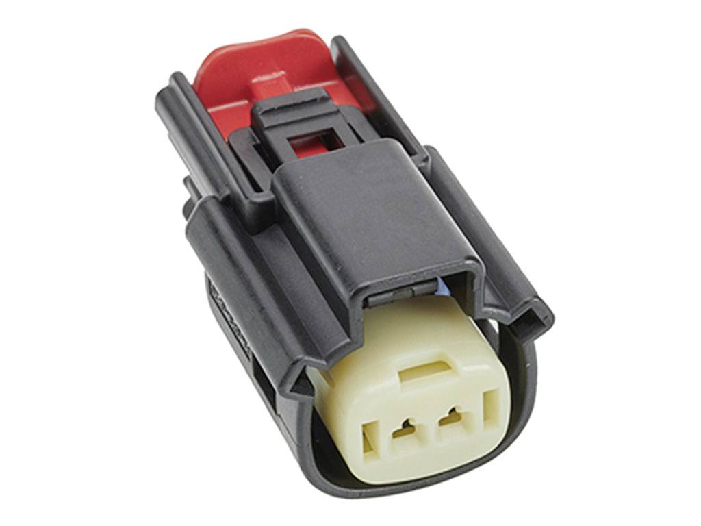 En svart och cremefärgad kontakt med ett rött clips, använd för elektriska anslutningar i fordonsapplikationer.