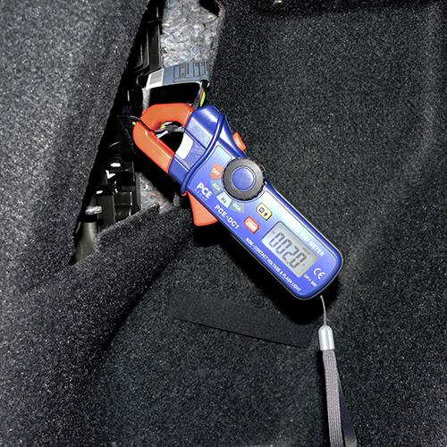 Ett tångramperemeter mäter strömmen i en kabel. Displayen visar '002.0'. Enheten är monterad i ett fordon.