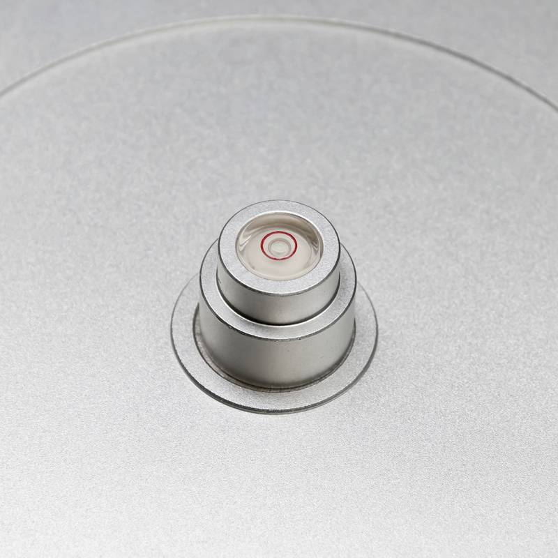 Närbild av ett silvergrått cylinderformat föremål med en liten, cirkelrund röd detalj i mitten. Slät, metallisk yta.