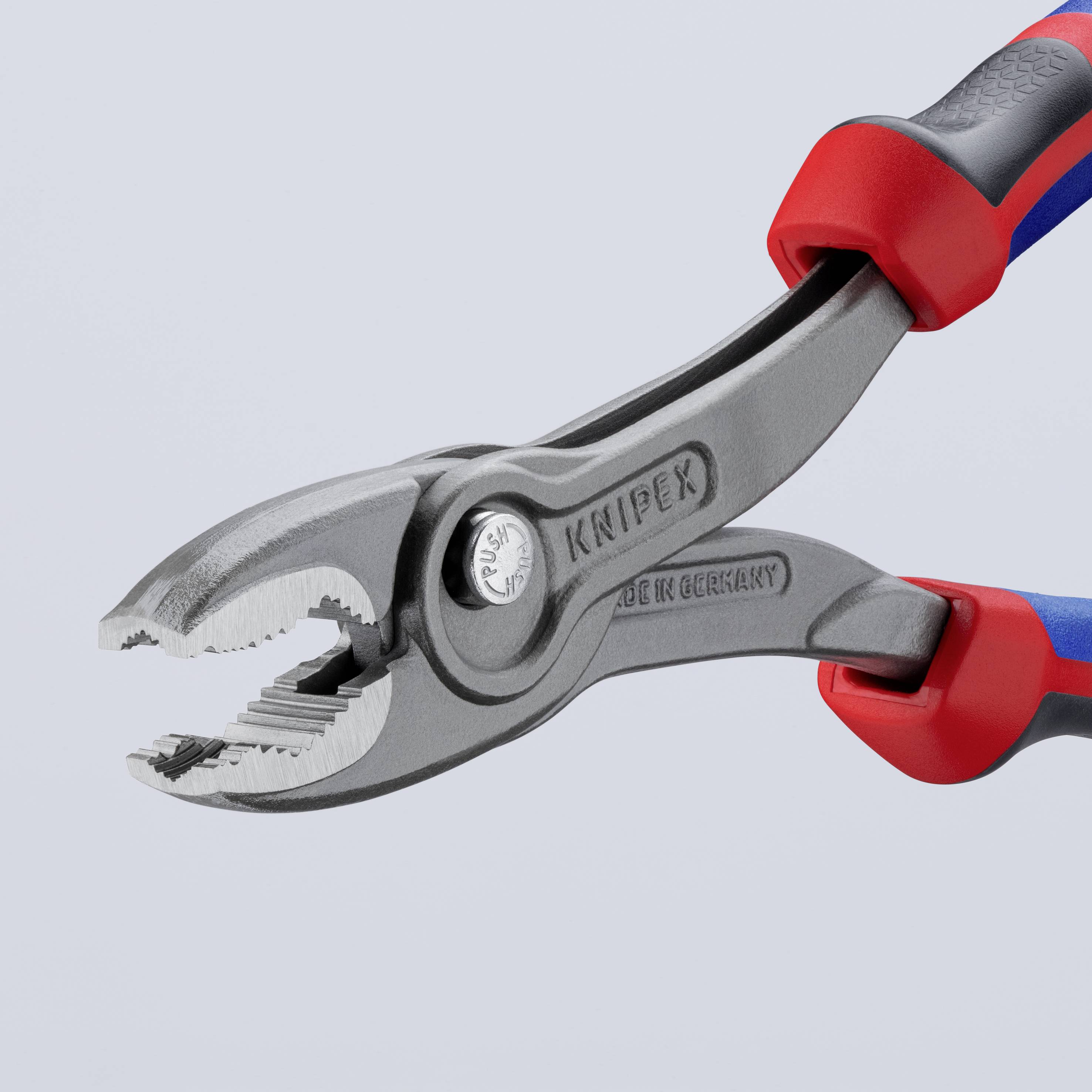 Tång med blå-röda handtag, halvöppen, visar metalliska tänder. Tillverkad av Knipex, 'Made in Germany' synligt på ytan.